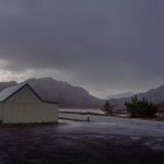 Temporary shelter under a stormy sky surrounded by mountains, hints of red and purple act as lowlights across the image. the shelter over looks Loch Bad an Sgalaig